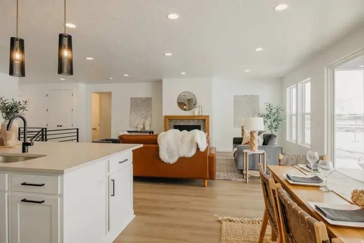 Open-concept living area featuring an eat-in kitchen island with pendant lighting, a fireplace with a wood-finish mantel, and wood-finish flooring