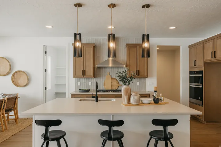 Kitchen island with a light-toned countertop, wood-finish cabinetry, stainless steel appliances, and a tiled backsplash