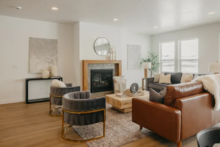 Spacious living area featuring a fireplace with a wood-wrapped mantel and tile surround, recessed lighting, expansive windows, and wood-finish flooring