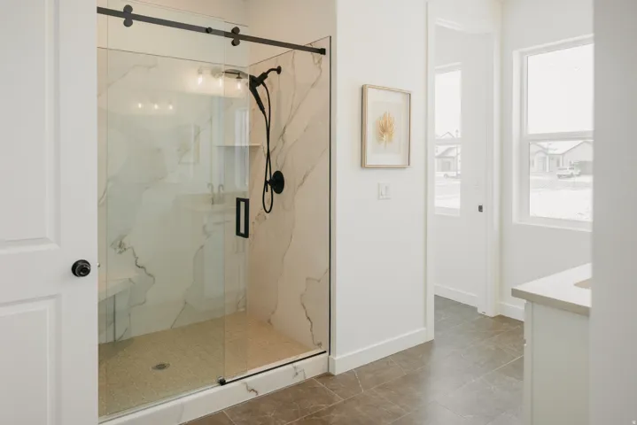 Enclosed glass shower with matte black fixtures, integrated bench, and marble-finish tile surround