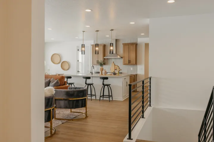 Kitchen island with seating, pendant lighting, wood-finish flooring, and a contemporary staircase railing