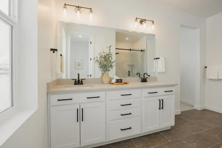 Dual vanity with quartz countertop, undermount sinks, matte black fixtures, and white cabinetry