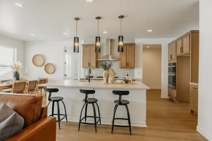 Kitchen featuring a center island, pendant lighting, wood-finish flooring, light wood cabinetry, and stainless steel appliances