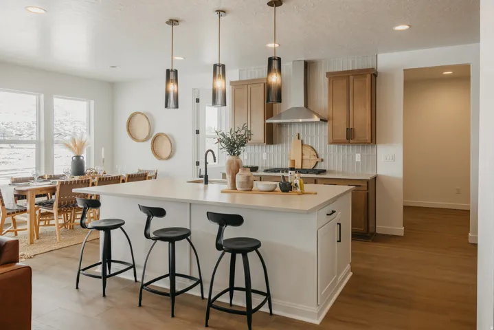 Kitchen island with an undermount sink and matte black faucet, wood-finish flooring, and light wood cabinetry with a tile backsplash
