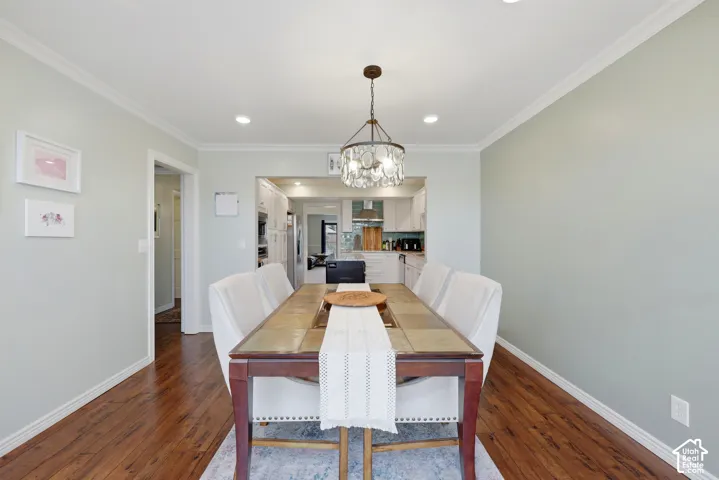 Open-concept dining area featuring wood-finish flooring, recessed lighting, and a decorative chandelier