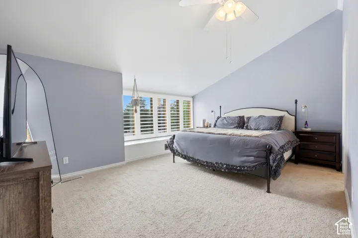 Vaulted ceiling with a ceiling fan, carpeted flooring, and a window seat with plantation shutters