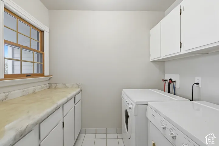 Laundry area featuring white cabinetry, a light-toned countertop, and grid-patterned floor tiles