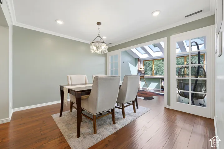 Hardwood-finish flooring, recessed lighting, crown molding, crystal chandelier, and French doors