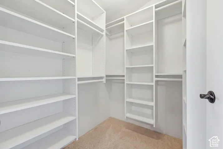 White built-in shelving, multiple hanging rods, and light-colored carpeting