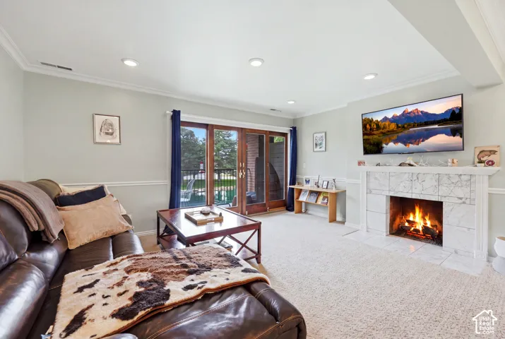 Living space with crown molding, recessed lighting, chair rail molding, a marble surround fireplace, and wood-frame sliding glass doors