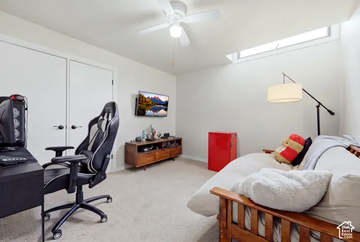 Recessed skylight, ceiling fan, white paneled doors, wall-mounted television, and carpeted flooring