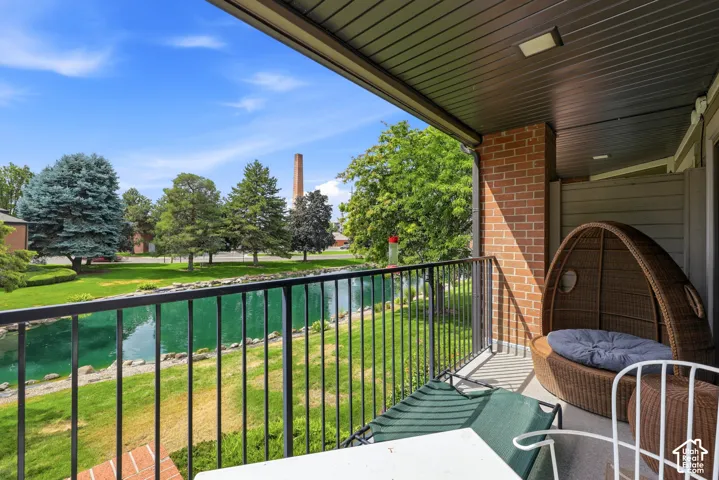 Covered balcony with black metal railings, a brick column, and a plank-style ceiling