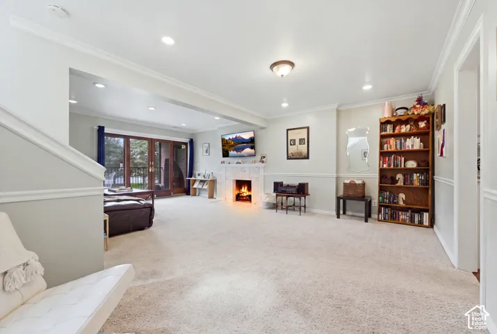 Recessed ceiling lighting, crown molding, and a fireplace with a stone surround