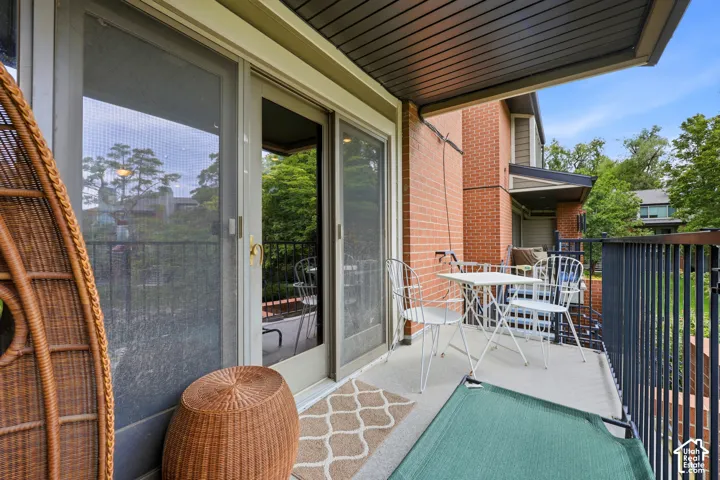 Outdoor balcony with a solid railing, concrete flooring, and sliding glass door access