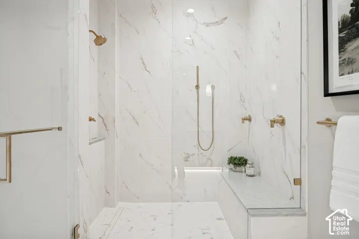 Walk-in shower with full-height veined wall tile, a built-in bench, and gold-finish fixtures