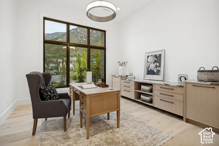 Expansive multi-pane window, light wood-finish flooring, built-in cabinetry with stone countertops, recessed shelving, and a modern ceiling fixture