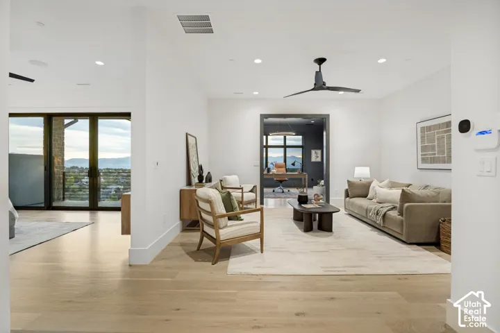 Light wood-finish flooring throughout, recessed ceiling lighting, modern ceiling fan, and a separate dedicated office space