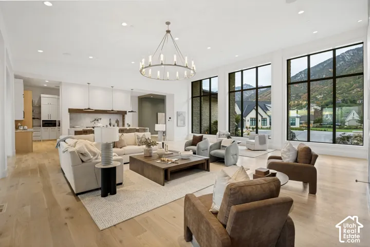 Open-concept living space featuring high ceilings, light wood-finish flooring, and a large chandelier