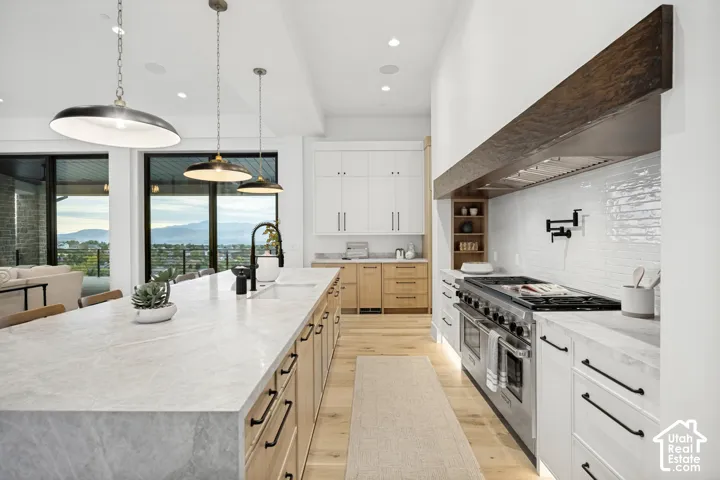 Expansive island with light-toned countertop, wood-finish cabinetry, and contemporary pendant lighting