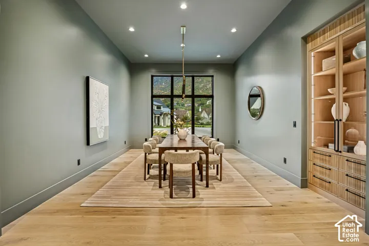 Recessed lighting, wood-finish flooring, full-height window, built-in display cabinetry with glass doors, and a linear pendant light fixture
