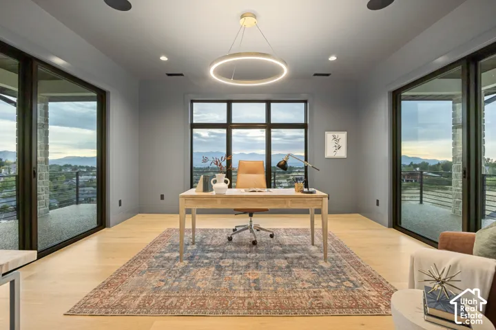 Expansive windows, light wood-finish flooring, recessed lighting, and a contemporary chandelier