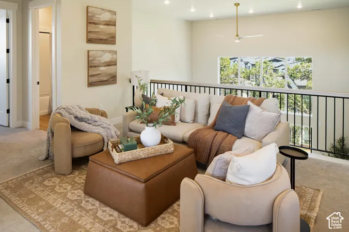 Carpeted loft area featuring a black metal railing, recessed lighting, and a modern ceiling fan