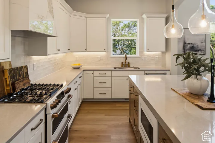 Kitchen featuring white shaker cabinetry, light-toned countertops, a gas range, and wood-finish flooring