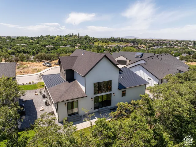 Modern exterior architecture featuring a prominent two-story window array, dark metal roofing, and a gravel patio area