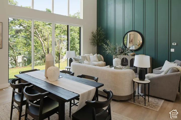 Expansive windows, light wood-finish flooring, and a dining area with a dark wood table