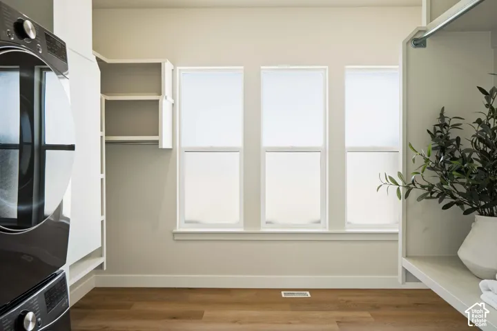 Wood-finish flooring with white baseboards, three windows with white frames, built-in shelving, and a built-in hanging rod