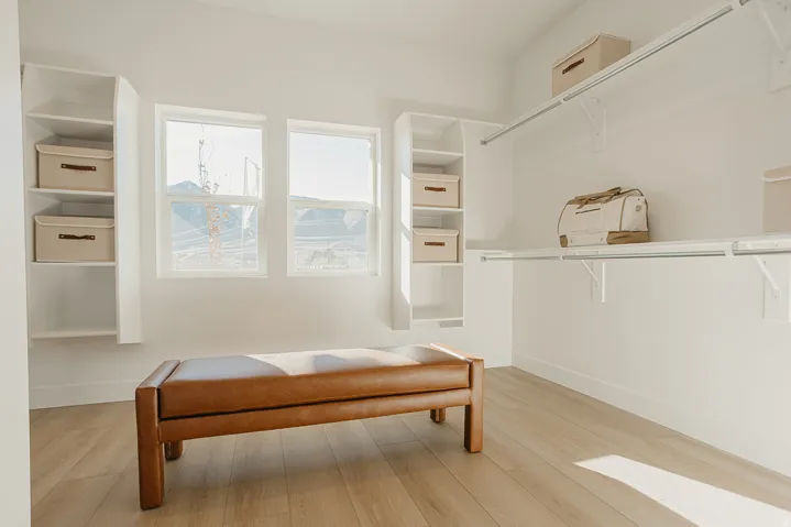 Built-in shelving units, two windows, wood-finish flooring, and white walls