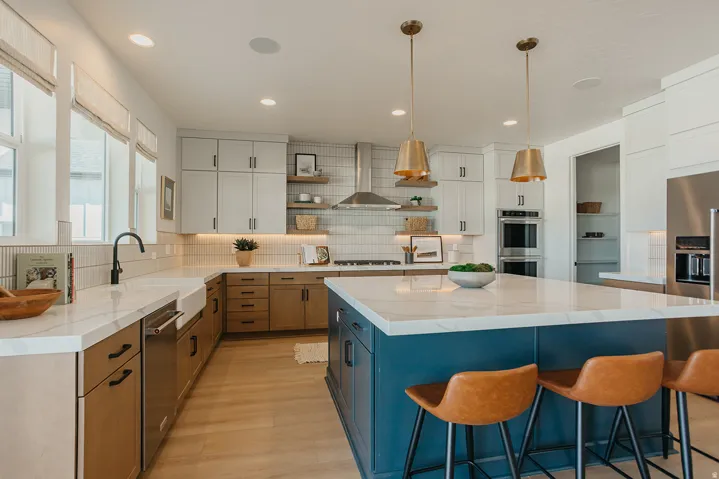 Gourmet kitchen with a large island, white countertops, built-in stainless steel appliances, wood-finish flooring, and ample cabinetry