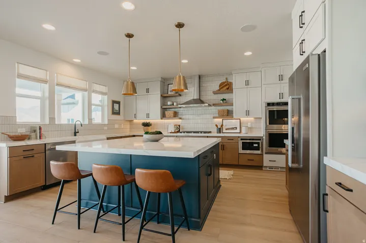 Spacious kitchen with a large center island, built-in stainless steel appliances, two-tone cabinetry, wood-finish flooring, and pendant lighting