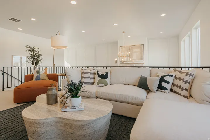 Recessed ceiling lighting, wrought iron railing, decorative wall paneling, and a contemporary chandelier