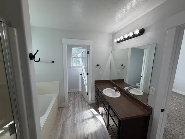 Dual vanity with integrated sinks, ample storage cabinetry, full-width mirror, and multi-bulb vanity light fixture