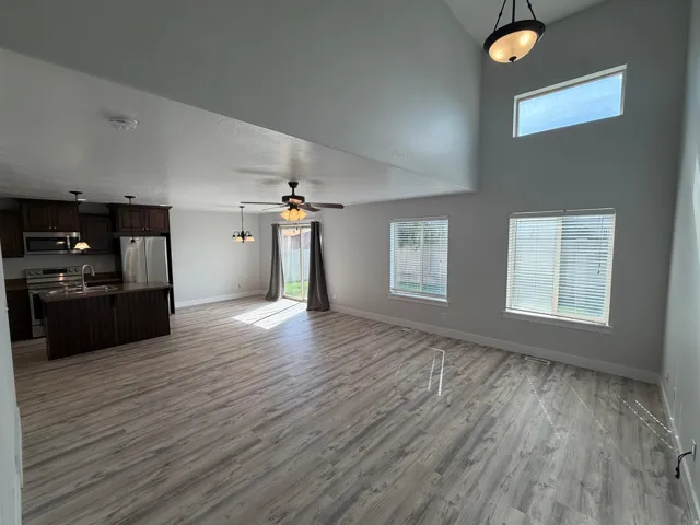 Vaulted ceilings, wood-finish flooring, dark wood cabinetry, stainless steel appliances, and a kitchen island with a sink