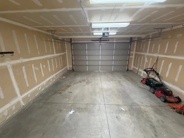 Concrete flooring with an overhead garage door, equipped with a garage door opener