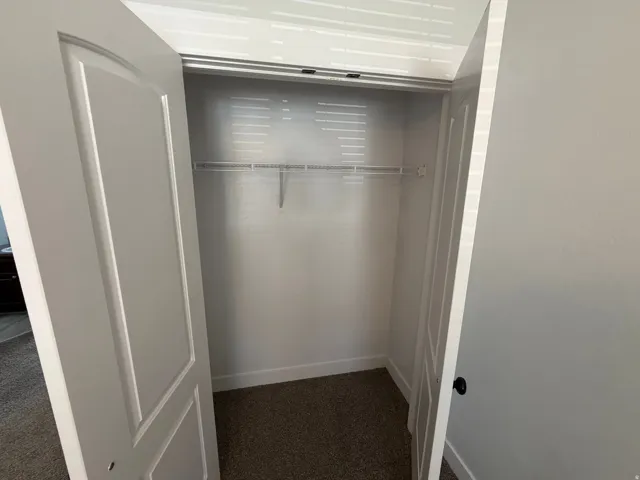 White interior doors opening to a closet with wire shelving and a hanging rod, featuring carpeted flooring