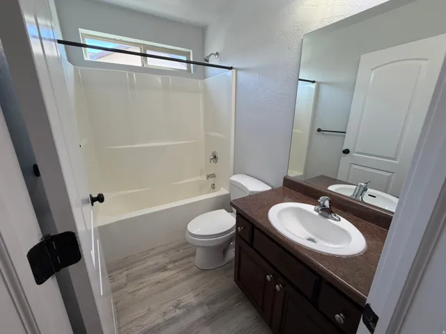 Bathroom featuring a spacious single vanity with a brown countertop, white oval sink, and chrome faucet