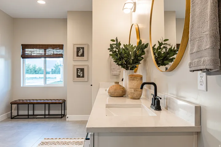 Vanity with an integrated sink, polished countertop, matte black faucet, and oval mirror