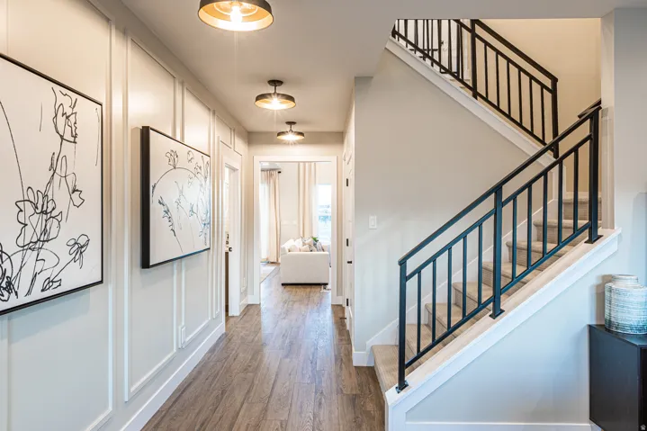 Wood-finish flooring, wainscoting accent wall, recessed lighting, and a staircase with metal railings