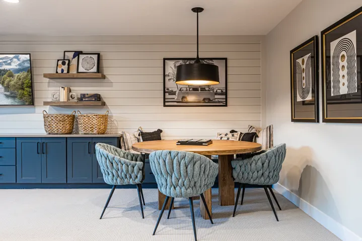 Built-in seating with shiplap wall detail, suspended black drum pendant light, built-in cabinetry with stone countertop, and two floating wood shelves