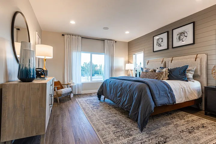 Wood-finish flooring, accent wall with horizontal paneling, multiple recessed ceiling lights, and expansive window with white drapery
