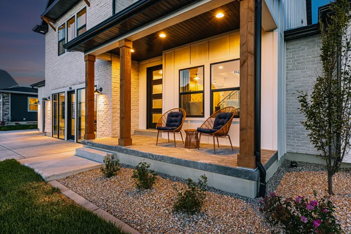 Covered porch with exposed wood columns, brick facade, recessed lighting, and a modern entry door