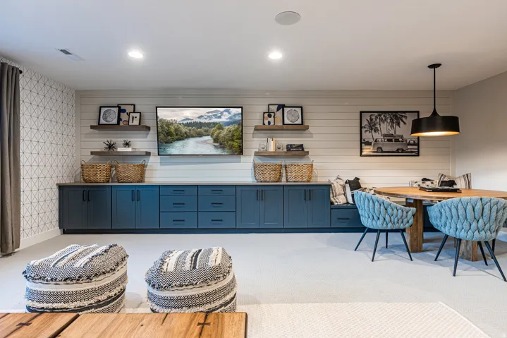 Built-in cabinetry with ample storage, integrated wall-mounted television, recessed lighting, accent wall with geometric wallpaper, and a built-in dining nook with bench seating