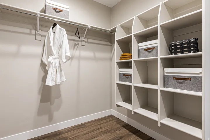 Custom closet system featuring open shelving, a hanging rod, and wood-finish flooring