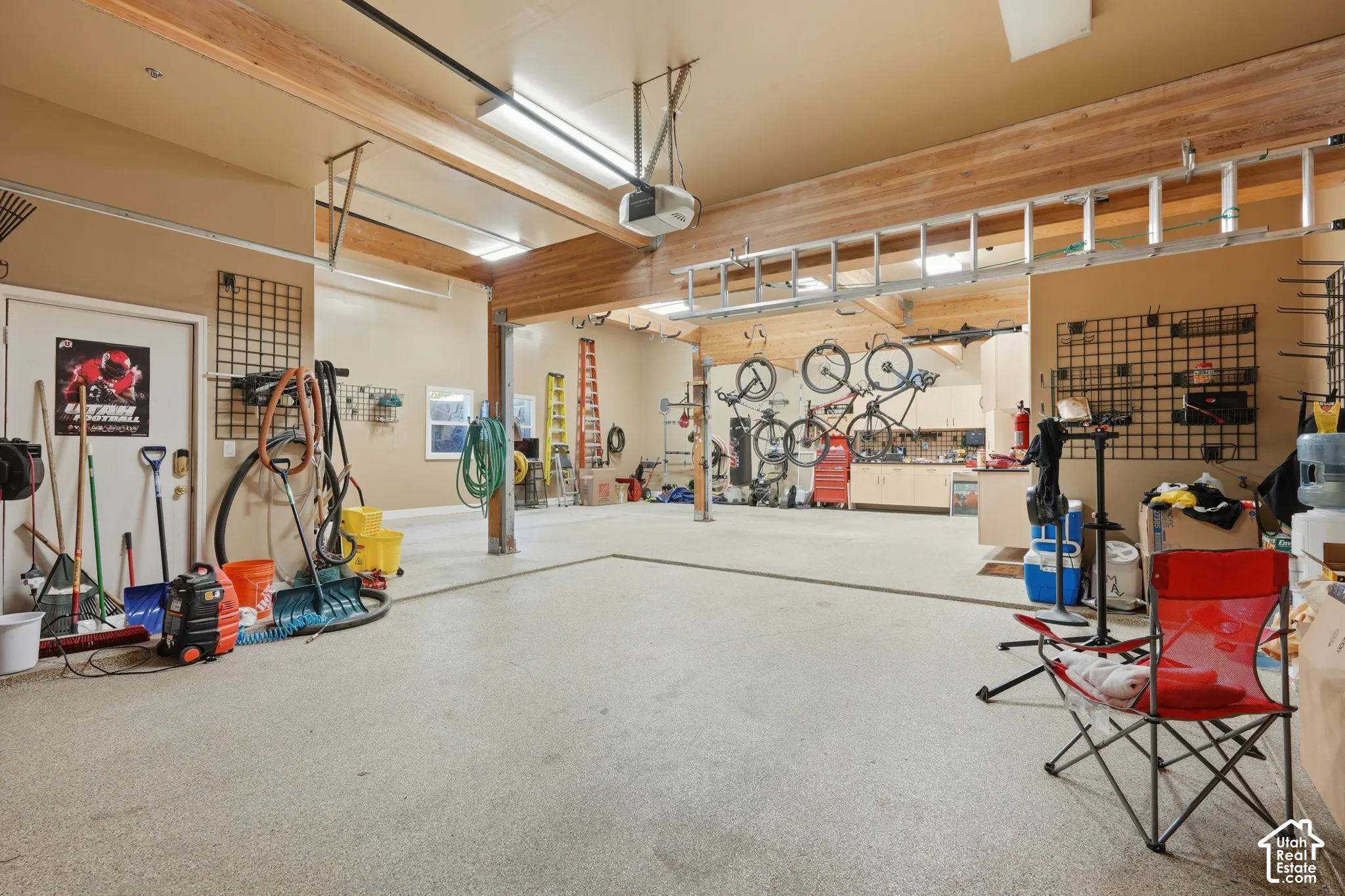 Spacious garage with exposed wood beams, overhead fluorescent lighting, and a durable speckled floor finish