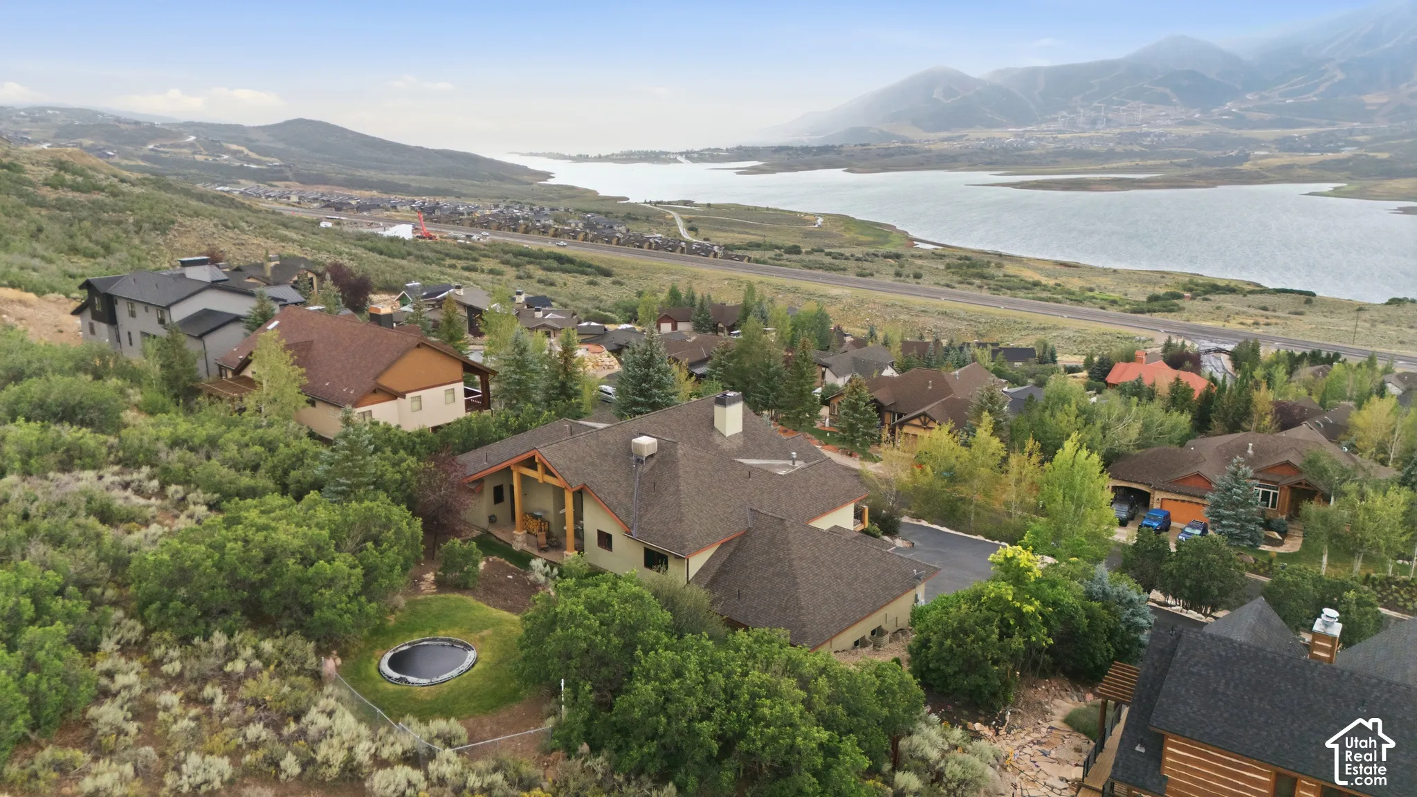 Spacious property featuring a large lawn, mature trees, and a distant lake with mountains