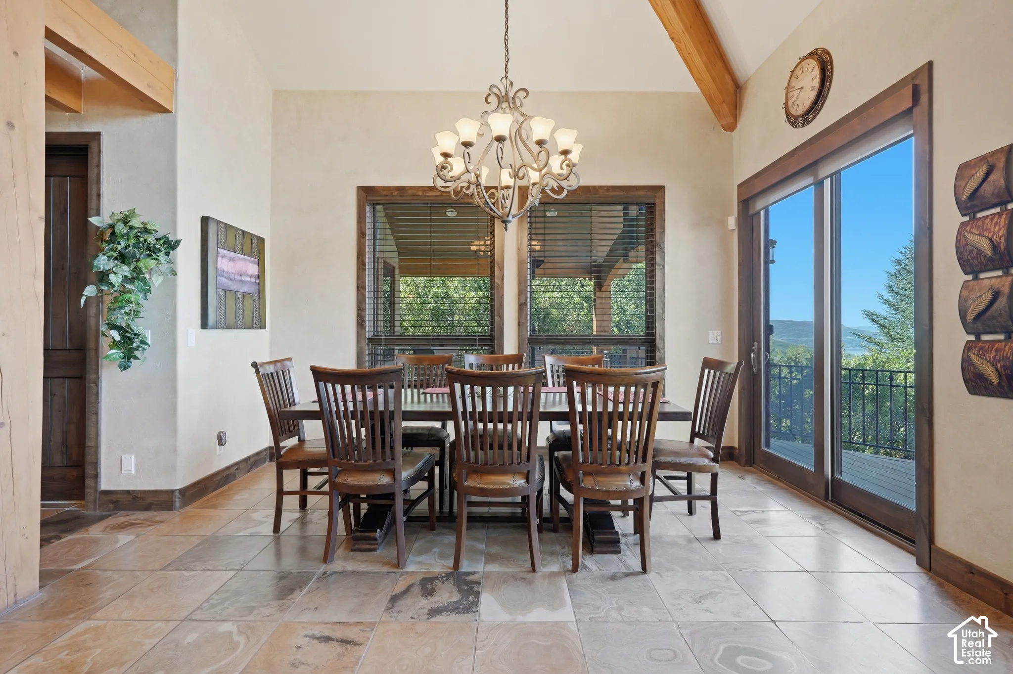 Dining area featuring vaulted ceilings with exposed wood beams, tile flooring, and a decorative chandelier
