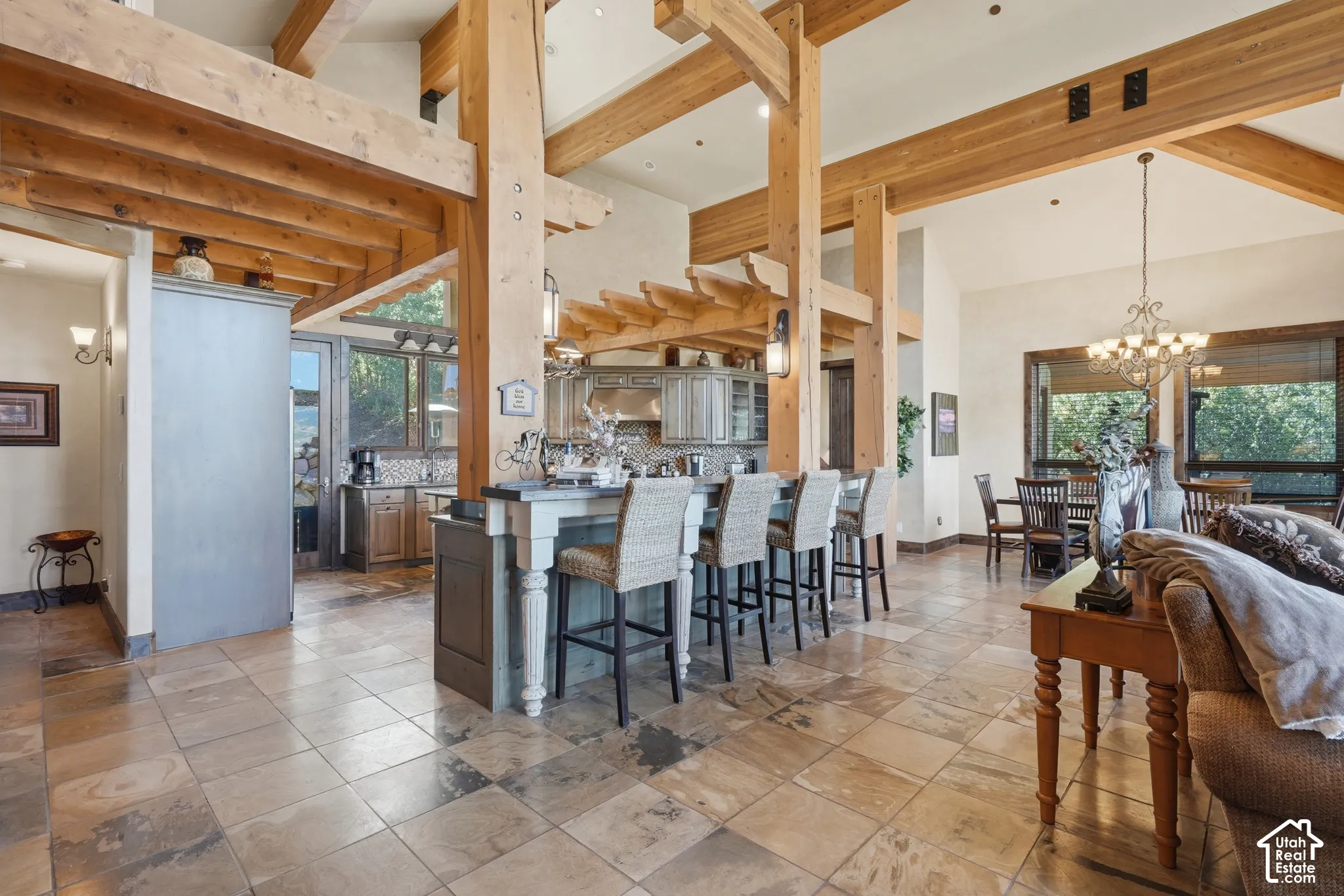 Vaulted ceilings with exposed wood beams, tile flooring, kitchen island with seating, built-in cabinetry, and large windows